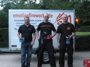 Drei Pyrotechniker vor Anhänger mit Firmenlogo