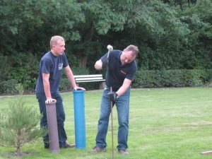 Zwei Männer arbeiten mit Hammer im Garten