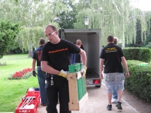 Männer laden Equipment aus Transporter im Garten aus